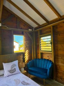 a bedroom with a blue chair and a bed at La pause verte bungalow in Sainte-Anne