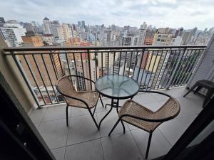 a balcony with a table and chairs and a view of a city at Conforto no Largo do Arouche 77 c Varanda, Lazer e Vista A 250m do Metrô in São Paulo