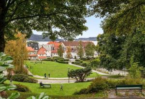 a park with people sitting on benches in the grass at Delightful Bryggen Apartment - Minimum Age 25 in Bergen +12 photos