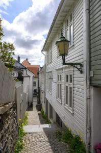 Un callejón entre dos casas blancas con una farola. en Delightful Bryggen Apartment - Norwegians Minimum Age 25, en Bergen