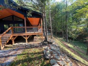 Ruth's Place Tiny Home Retreat 1 mile to town في Burnsville: كابينة في الغابة مع شرفة كبيرة