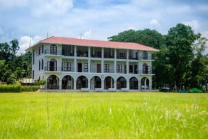 a large white building with a grass field at The Pavilion at Riverside Park in Kāundia