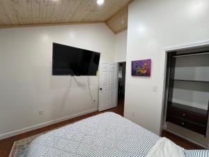 Ruth's Place Tiny Home Retreat 1 mile to town في Burnsville: غرفة نوم مع سرير وتلفزيون بشاشة مسطحة على الحائط