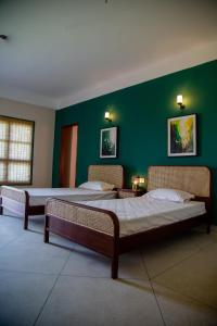 two beds in a room with a green wall at The Pavilion at Riverside Park 
