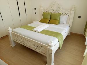 a white bed with green and white pillows on it at Johari One Bedroom 11th Floor Apartment-Lavington in Nairobi +39 photos