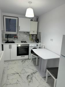 a kitchen with white cabinets and a marble floor at Fox Apartament in Râmnicu Vâlcea