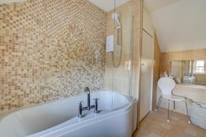 a bathroom with a tub and a shower and a chair at Rose Cottage in Sedgeford +7 photos