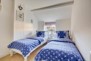 two beds in a room with blue and white sheets at Rose Cottage in Sedgeford