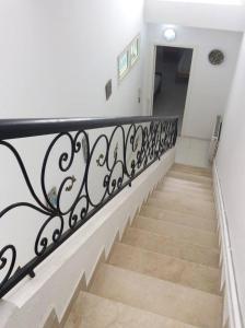 a stairway with a black railing on a white wall at Maison Myriam in Nabeul