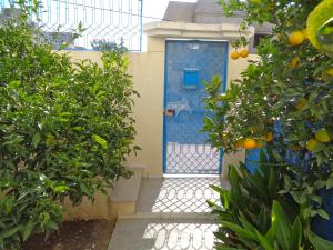 a blue door of a house with orange trees at Maison Myriam in Nabeul