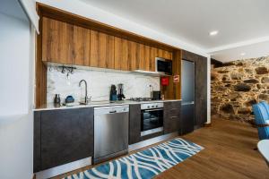 a kitchen with stainless steel appliances and wooden cabinets at Trilogia in Lousã