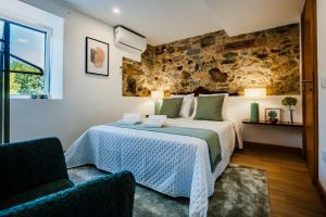 a bedroom with a bed and a stone wall at Trilogia in Lousã +22 photos