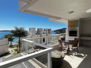 a balcony with a table and chairs and the ocean at Res. Signus in Bombinhas