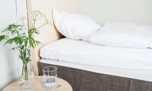 a bed with white sheets and two glasses on a table at Hotel Akerlund in Jokkmokk