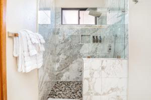 a bathroom with a shower with a glass door at New baths king bed open & tranquil pool hot tub in Waikoloa