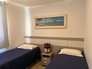 a room with two beds and a painting on the wall at Res. Signus in Bombinhas +22 photos
