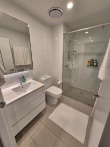 a white bathroom with a shower and a toilet at Private Bedroom & Bathroom in an Amazing Shared Brisbane Apartment in Brisbane