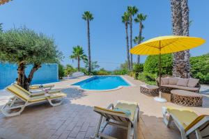 une terrasse avec des chaises et un parasol ainsi qu'une piscine dans l'établissement Villa Monte da Torre, à Loulé