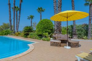 un parasol jaune et des chaises à côté d'une piscine dans l'établissement Villa Monte da Torre, à Loulé