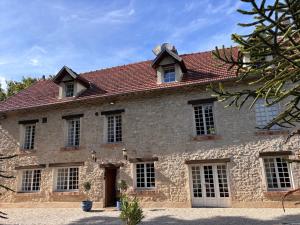 ein altes Steinhaus mit rotem Dach in der Unterkunft Maison de campagne proche de Paris in Vienne-en-Arthies