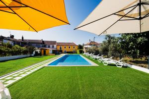 a pool with chairs and umbrellas on a lawn at Trilogia in Lousã