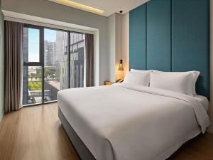 a large white bed in a room with a large window at Novotel Living Saigon South in Ho Chi Minh City +40 photos