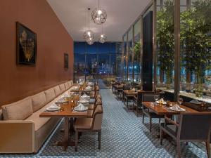 a restaurant with wooden tables and chairs and windows at Movenpick Diyarbakir in Diyarbakır