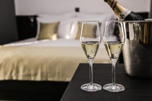 two glasses of white wine on a table next to a bed at Garni Hotel Zen in Niš