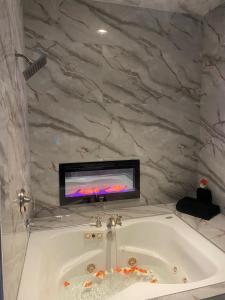 a bathroom with a tub with a tv on the wall at DC Private Room Luxury Spa Bath in Washington, D.C.