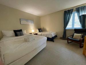 a hotel room with two beds and a chair at Le Belvedère Mont-Tremblant in Mont-Tremblant