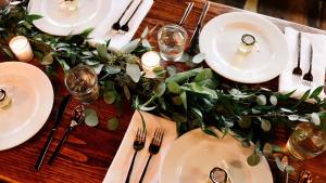 a wooden table topped with white plates and silverware at Kimpton Mirador Pacific Grove Monterey by IHG in Pacific Grove +2 photos