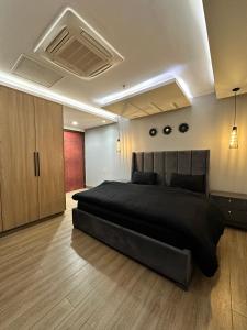 Schlafzimmer mit einem großen schwarzen Bett und Holzböden in der Unterkunft Executive Apartments at Goldcrest Mall DHA phase 4 by Nirvana Nests in Lahore