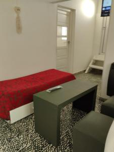 Habitación con cama roja, mesa y puerta en Casa lajas, en Villa María