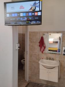 Un televisor en un baño con lavabo e inodoro. en Casa lajas, en Villa María