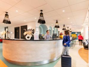 a man and a woman standing at a bar at Ibis Styles Paris Saint Denis Pleyel in Saint-Denis