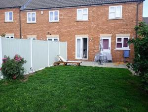 a house with a fence and a bench in the yard at Charming Tewkesbury Holiday Home - Gateway to the Cotswolds in Tewkesbury