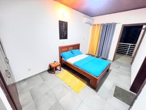 a bedroom with a bed with blue sheets and a window at Yafé Dragage 22 VIP in Yaoundé