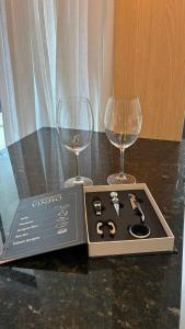 two wine glasses and a box on a table at Apto Kairós Beach Stay - Piscina e Churrasqueira in Itapema