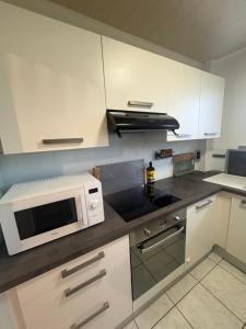 a kitchen with white cabinets and a microwave oven at Le Cerf in Wintzenheim