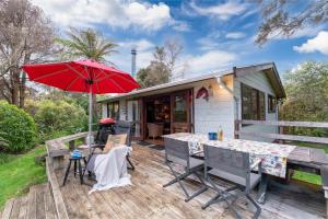 a house with a deck with a table and an umbrella at Hatepe Lake Taupo Retreat in Motutaiko Island