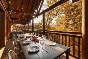 een tafel op het terras van een veranda met uitzicht op bomen bij Indoor Pool - Epic Game Room - MiniGolf - 24 Guests - 8 Bedrooms in Sevierville +54 foto's