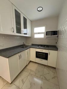 a kitchen with white cabinets and a sink and a microwave at Evoke suites apartment in central madinaty 2 bedroom in Madinaty