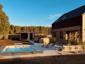 a backyard with a pool and chairs and a building at Blissko - boho willa z basenem, sauną i jacuzzi in Węgierskie