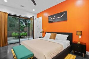 a bedroom with an orange wall with a bed and a table at South Lamar Luxe Creekside Retreat with POOL in Austin