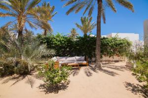 een bank op het strand onder palmbomen bij Villa Dar Salama, 3 Chambres, Plage à 5 minutes in Midoun