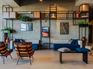 a living room with a blue couch and chairs at ibis Lavras in Lavras