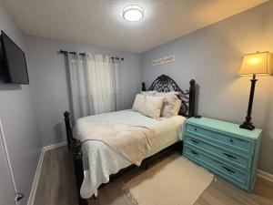 a bedroom with a bed with a blue dresser and a lamp at Stay beachy in Gulf Shores