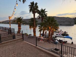 a beach with palm trees and a boat in the water at RIV A HOLIC in Bullhead City