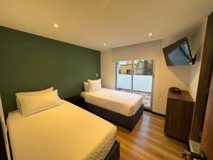 a hotel room with two beds and a window at Hotel Colonial Santa Barbara in Tunja
