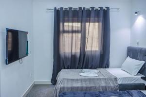 a room with a bed and a tv and a window at Lá Maison Jolly in Luanda +18 photos